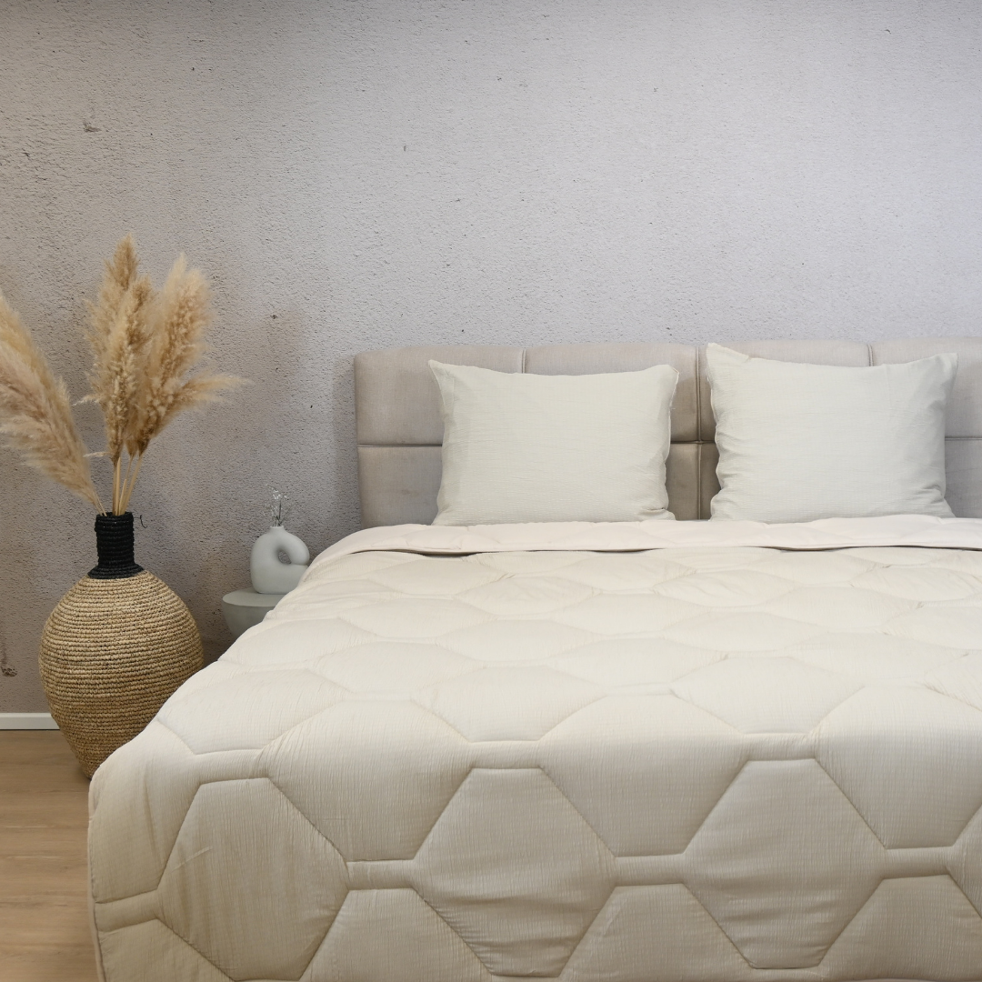 HappyBed Mousseline dekbed in sand color on beige bed with two pillows and decorative vase with pampas grass.