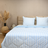 Light blue HappyBed zomerdekbed cooling summer duvet with breathable, silky nylon fabric on a bed with matching pillows in a modern bedroom setting