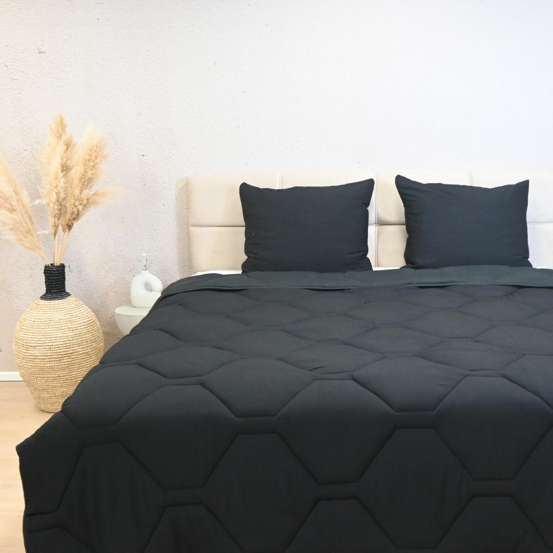 Black HappyBed Mousseline dekbed on a bed with matching black pillows in a modern bedroom setting