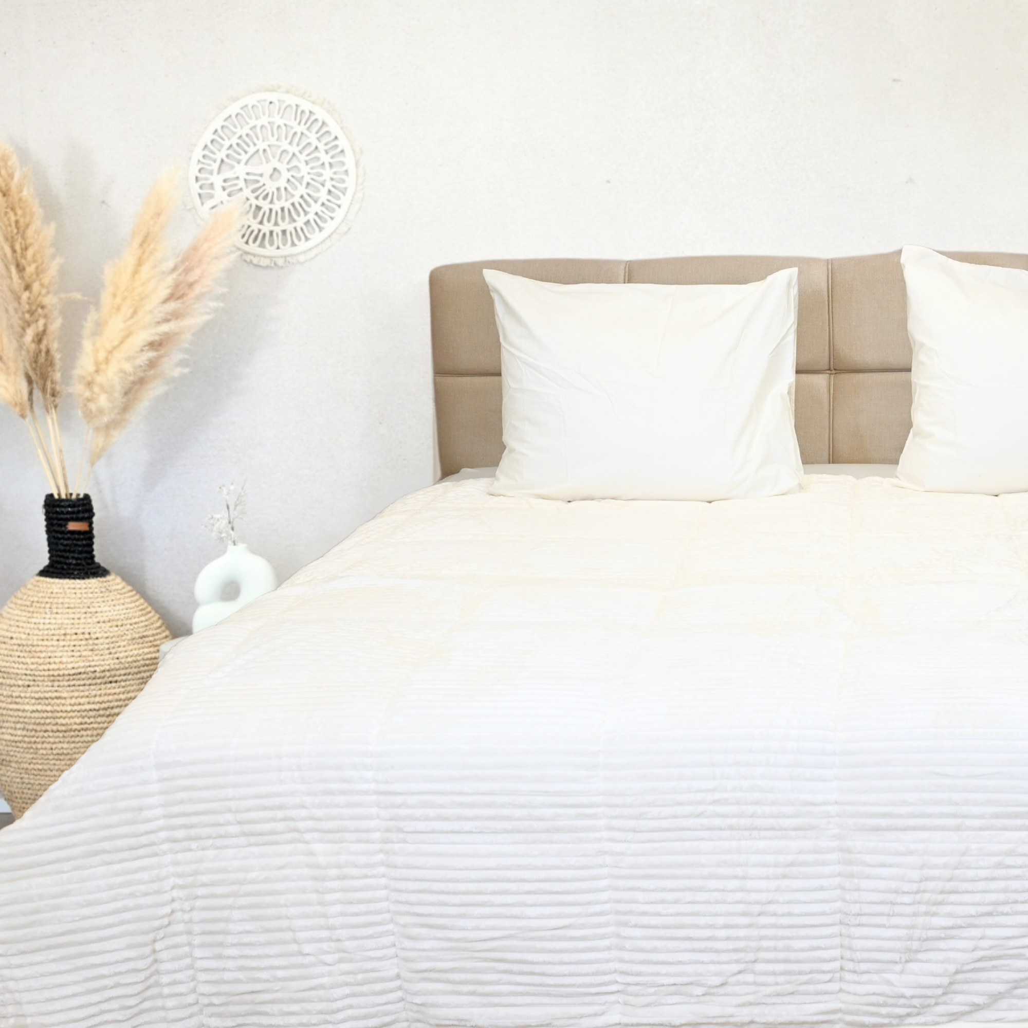 Snow White bedding set on a double bed with textured design, decorative pillows, and natural decor.