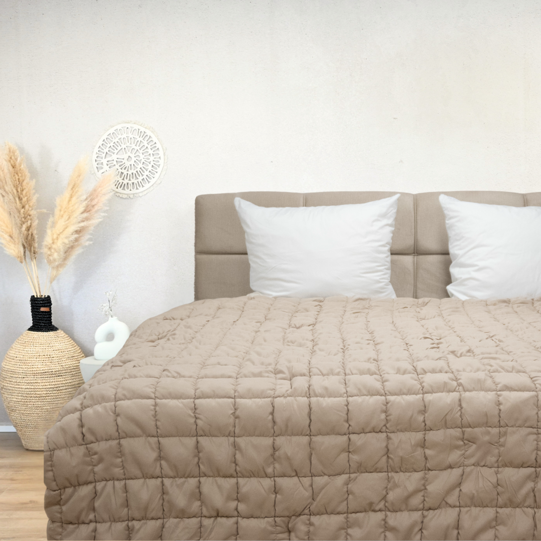 HappyBed Puffy grey quilted all-season hypoallergenic comforter on bed with beige headboard and decorative vase in modern bedroom