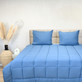 HappyBed Bluestone all-season bedstead with blue cover and matching pillows in a cozy bedroom setting.
