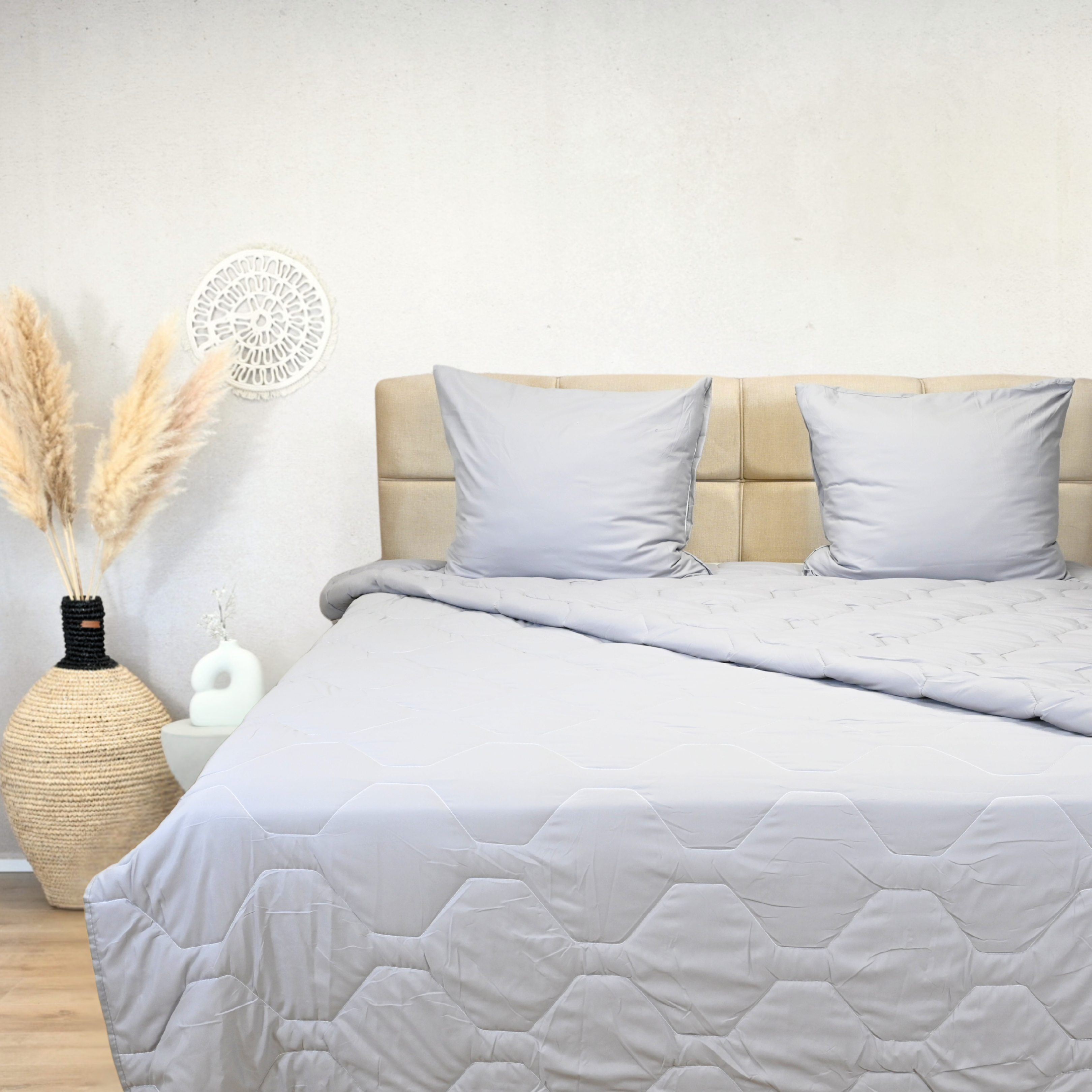 Grey adjustable duvet on a beige bed with decorative pillows, suitable for all seasons.