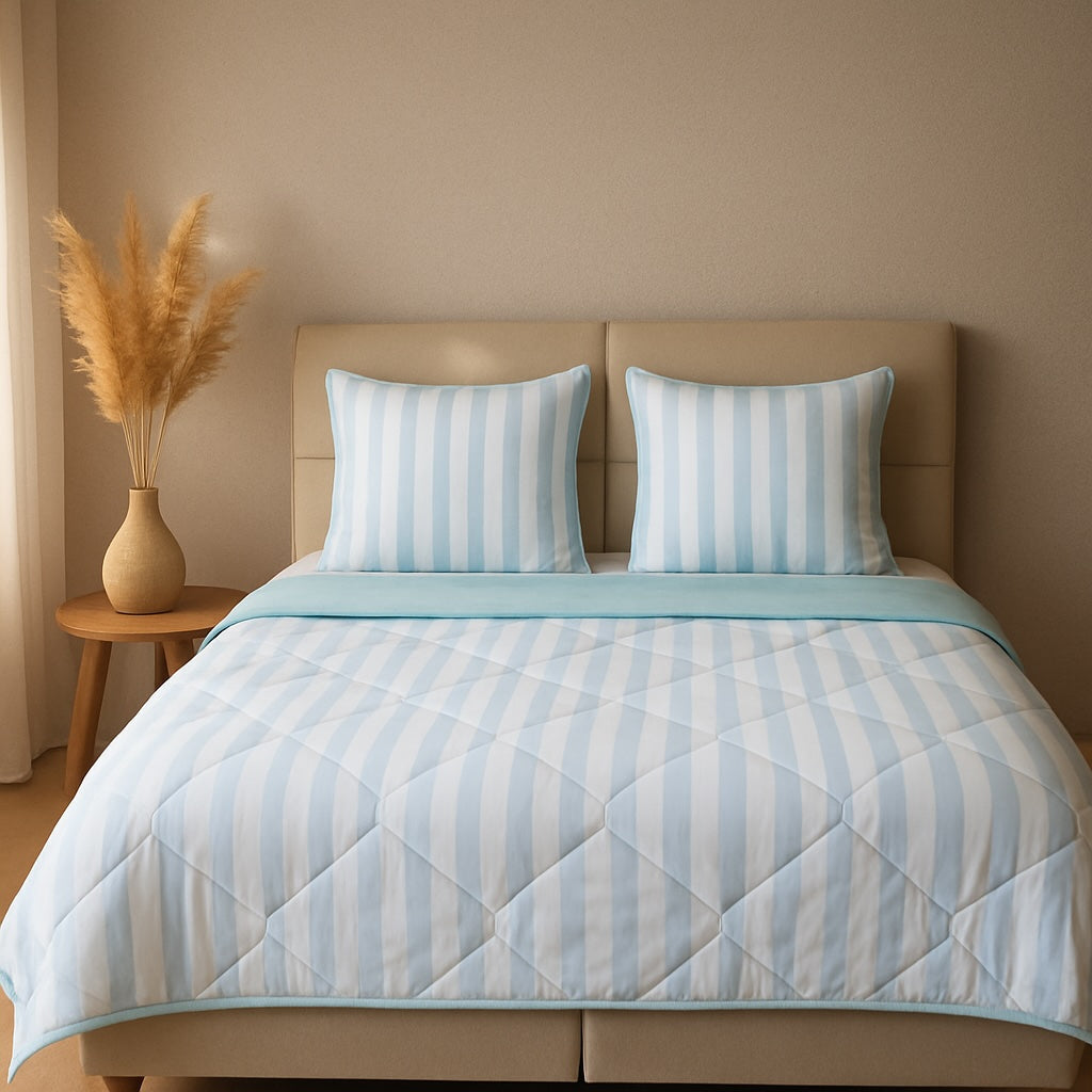 Light blue HappyBed zomerdekbed on a bed with striped pillows, providing cooling comfort for summer nights.