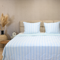 HappyBed zomerdekbed in lichtblauw op bed, verkoelend en ademend, sierkussens, neutrale slaapkamerinrichting.