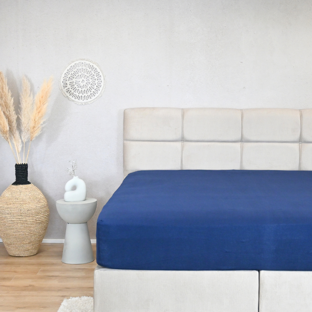 HappyBed premium jersey fitted sheet in indigo blue on a bed, showcasing a smooth, wrinkle-free fit.