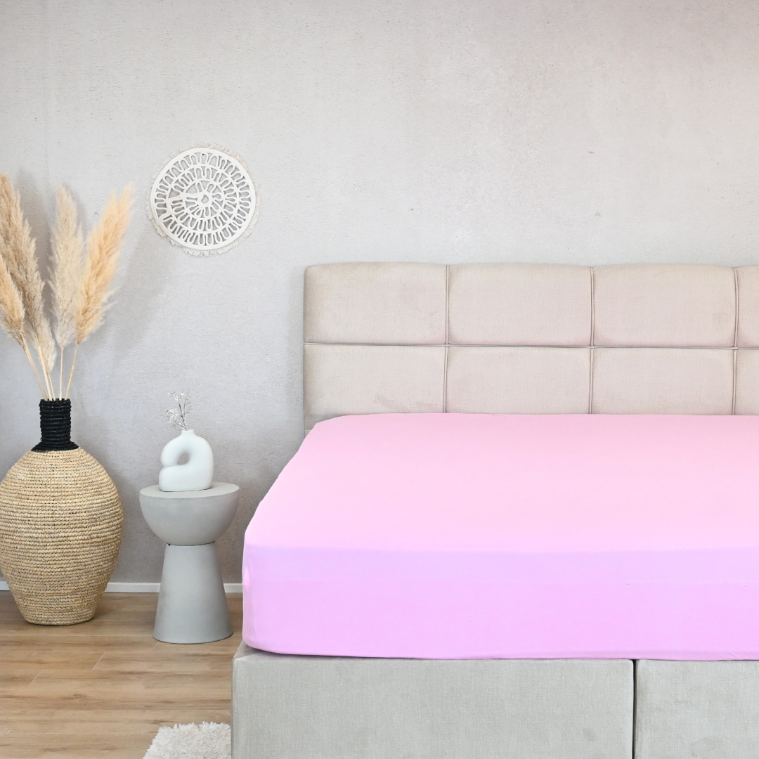 HappyBed premium jersey hoeslaken in pink on a bed with neutral decor.