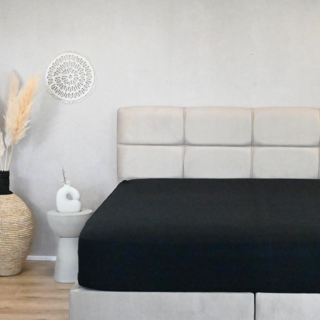 HappyBed premium jersey hoeslaken in anthracite on a bed, showcasing its wrinkle-free fit and luxurious style.